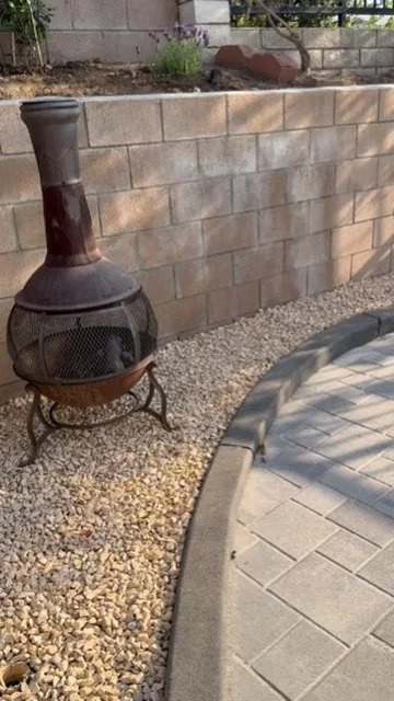 Chiminea standing on gravel beside a curved paver patio edge in Orange County, California