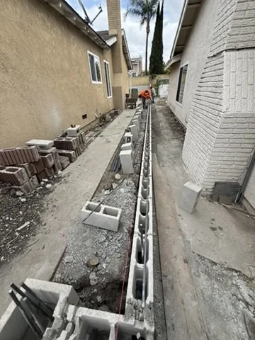 Open footing trench with block laid to the first course along a side yard in Orange County, California