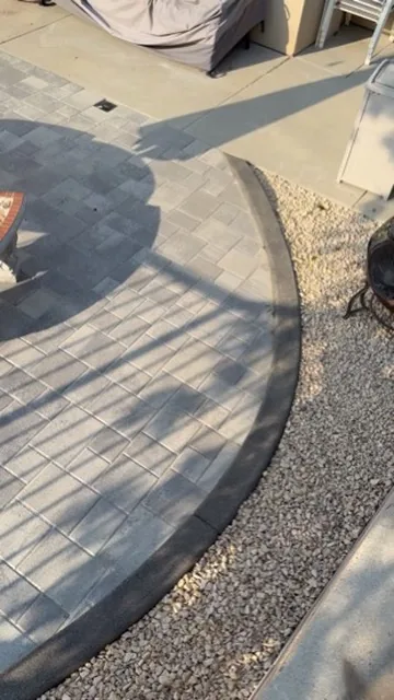 Paver patio with a curved cobble border set against decomposed granite in Orange County, California