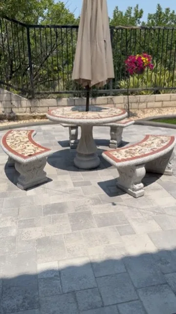 Paver patio with a cast stone table and benches under an umbrella in Orange County, California