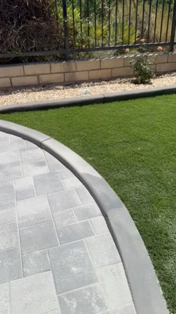 Paver walkway with a curved edge meeting an artificial turf lawn in Orange County, California
