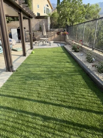 Artificial turf lawn running beside a covered patio and planted border in Orange County, California
