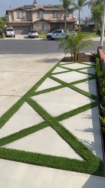 Ribbon driveway of concrete panels with artificial turf joints running out to the street in Orange County, California