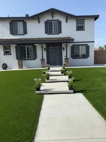 Concrete stepping panel walkway crossing an artificial turf front lawn to the front door in Orange County, California